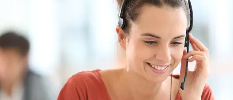 A smiling customer service adviser taking a call on a headset