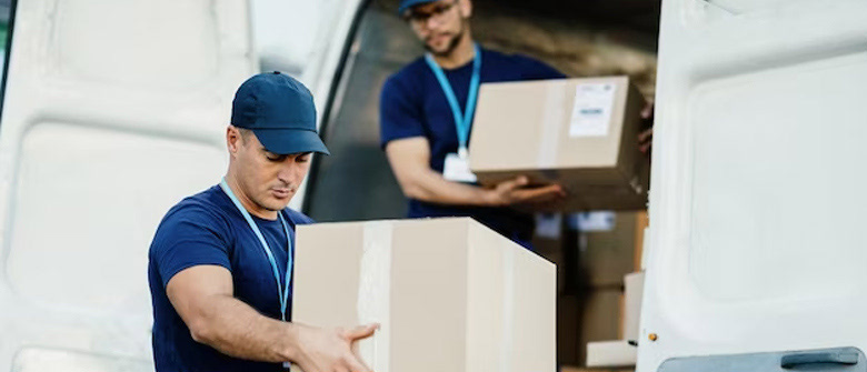 Two drivers unloading boxes from the back of a delivery van